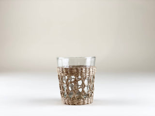 Clear glass tumbler with seagrass wrap on a white background.