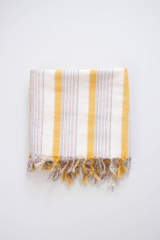 Home & Loft Turkish Towel White with wider yellow stripes and thin multicolored stripes with tassels.
