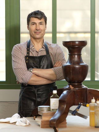 Christophe Pourny in a workshop with a wooden table base and tools
