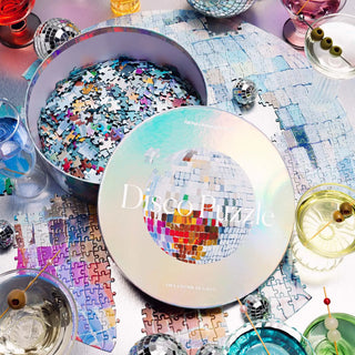 Piecework round 750-piece puzzle featuring a prismatic painting by artist Ashley Treece. Finished with a holographic sheen that mirrors the shimmer of a real disco ball.  Completed puzzle is 22 inches across packaged in a circular box 8 inches across and 1.8 inches tall 
