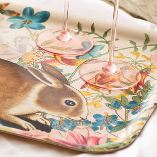 Two pink wine glasses on a decorative plate with a rabbit and floral design.