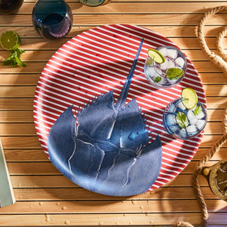 Red and white striped plate with blue crab design on a wooden surface