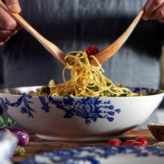 Person using wooden spoons to serve spaghetti from a Caskata Arcadia decorative bowl.