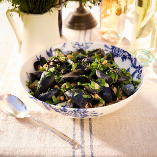 Caskata Arcadia Bowl of mussels with greens on a tablecloth with a spoon