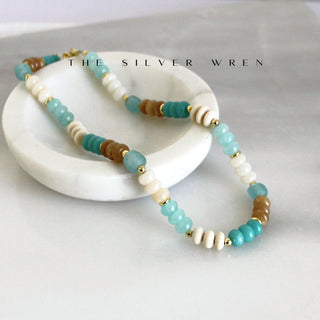  This hand-beaded gemstone necklace by The Silver Wren features calming turquoise, warm neutral tones, and gold filled accents. Lightweight and easy to layer, it’s a versatile everyday you will reach for again and again. 
natural dyed jade, recycled glass and wood beads •Adorned with 14kt gold filled accents •Beaded by hand just for you Water friendly •16 inch length plus a 2 inch extender for up to 18 inches.