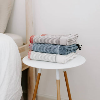 Stack of three Home & Loft turkish towels on a bedside table.