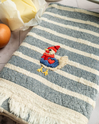 Striped towel with embroidered rooster design on a kitchen counter.