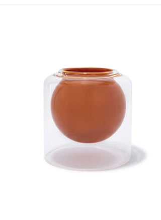 The Skeem Design candle features a suspended glass sphere that glows softly when lit, appearing weightless within its transparent outer vessel.