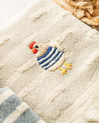 Embroidered rooster design on a textured fabric background