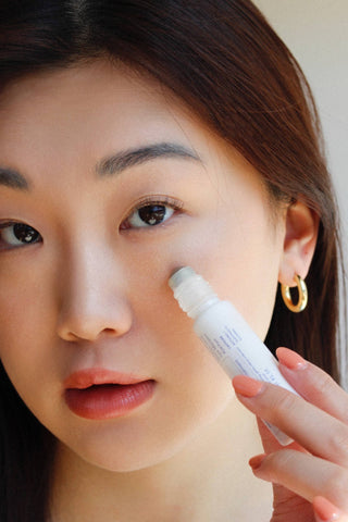 A cooling, roll-on eye serum with nourishing Greek yoghurt and a double shot of caffeine for under-eyes for noticeably diminished dark circles and puffiness to bring back the look of rested, hydrated skin. Key Benefits - Reduces dark circles - Depuffs undereye bags. Model using product. 