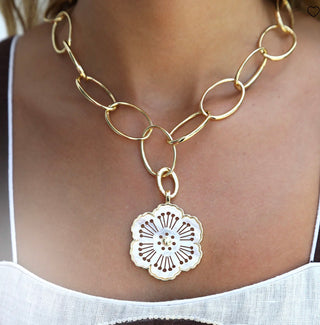Asha gold dipped rounded oval link chain necklace with a floral pendant on a person wearing a white top.