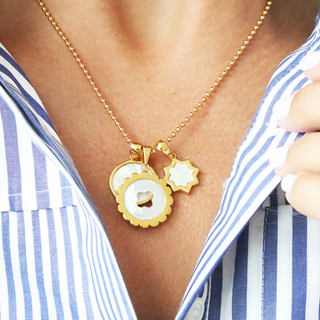 14k gold dipped and mother of pearl quatrefoil cutout. Shown on a chain with other charms. 