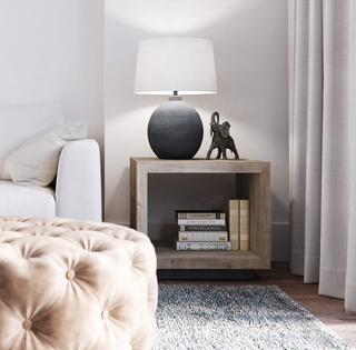 Grey organic shape table lamp with a white tapered drum shade. Pictured on a bedside table.