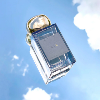 Perfume bottle labeled 'AIR' with gold top against a blue sky background
