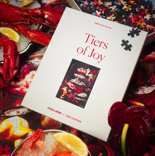 Piecework Puzzle box titled 'Tiers of Joy' with a seafood-themed cover on a table with lobsters and lemons.