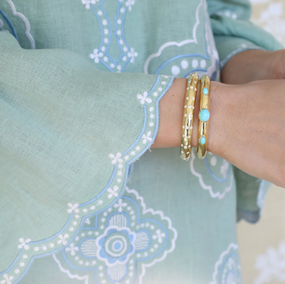 Asha gold dipped Loulou Sparkle Cuff pictured on a wrist with another Asha cuff with tuquoise blue stones.