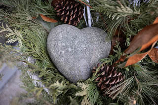 Heart-shaped stone surrounded by greenery and pinecones