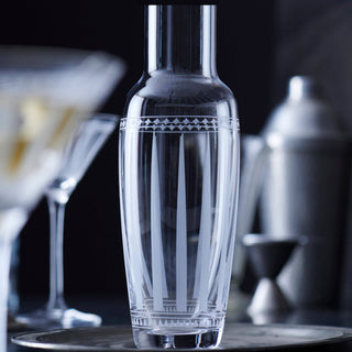 Clear glass carafe with geometric patterns on a bar counter with blurred background