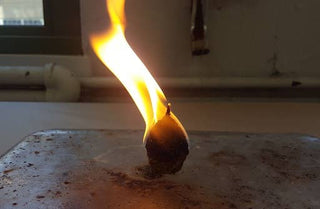 Flaming firestarter on a surface with a blurred background