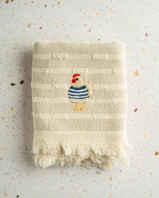 Textured towel with embroidered rooster design on a speckled surface