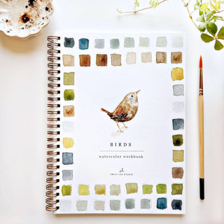 Emily Lex watercolor workbook with bird illustration on a white surface with a cup and plant.
