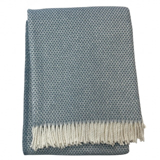Grain of rice folded blue throw blanket with white fringe on a white background