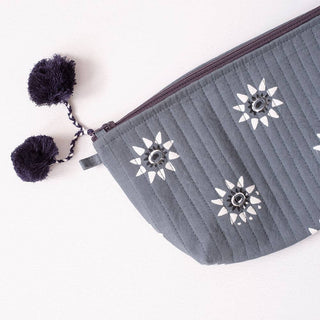 Gray pouch with floral patterns and pom-pom details on a white background