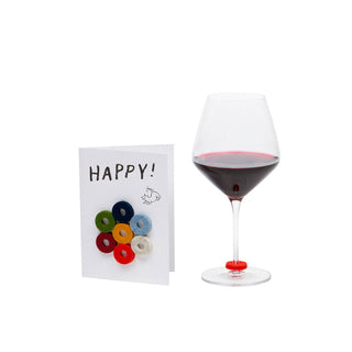Wine-Ote's Felt Wine Marker Note Cards are an extension of our best selling Merino wool felt wine markers Wine-O’s. Multicolored felt markers displayed on a Happy notecard alongside a glass of wine with a marker on the stem of the glass.