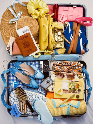 Open suitcase filled with travel items including shoes, a passport, and a camera.