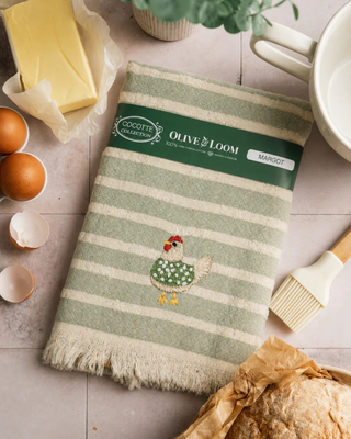 Olive & Loom 
Woven from 100% Turkish cotton, this towel features a soft, textured stripe design in warm neutral tones, finished with playful fringe and a sweet embroidered hen detail.