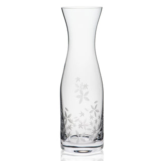 Clear glass carafe with floral etching on a white background