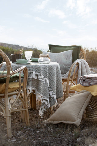 Outdoor dining setup with table, chairs, and decorative items in a natural setting.